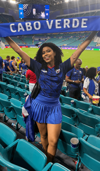 Braider Lorreta Rocha poses in the stands of the Cabo Verde World Cup game holding up a Cabo Verde scarf.